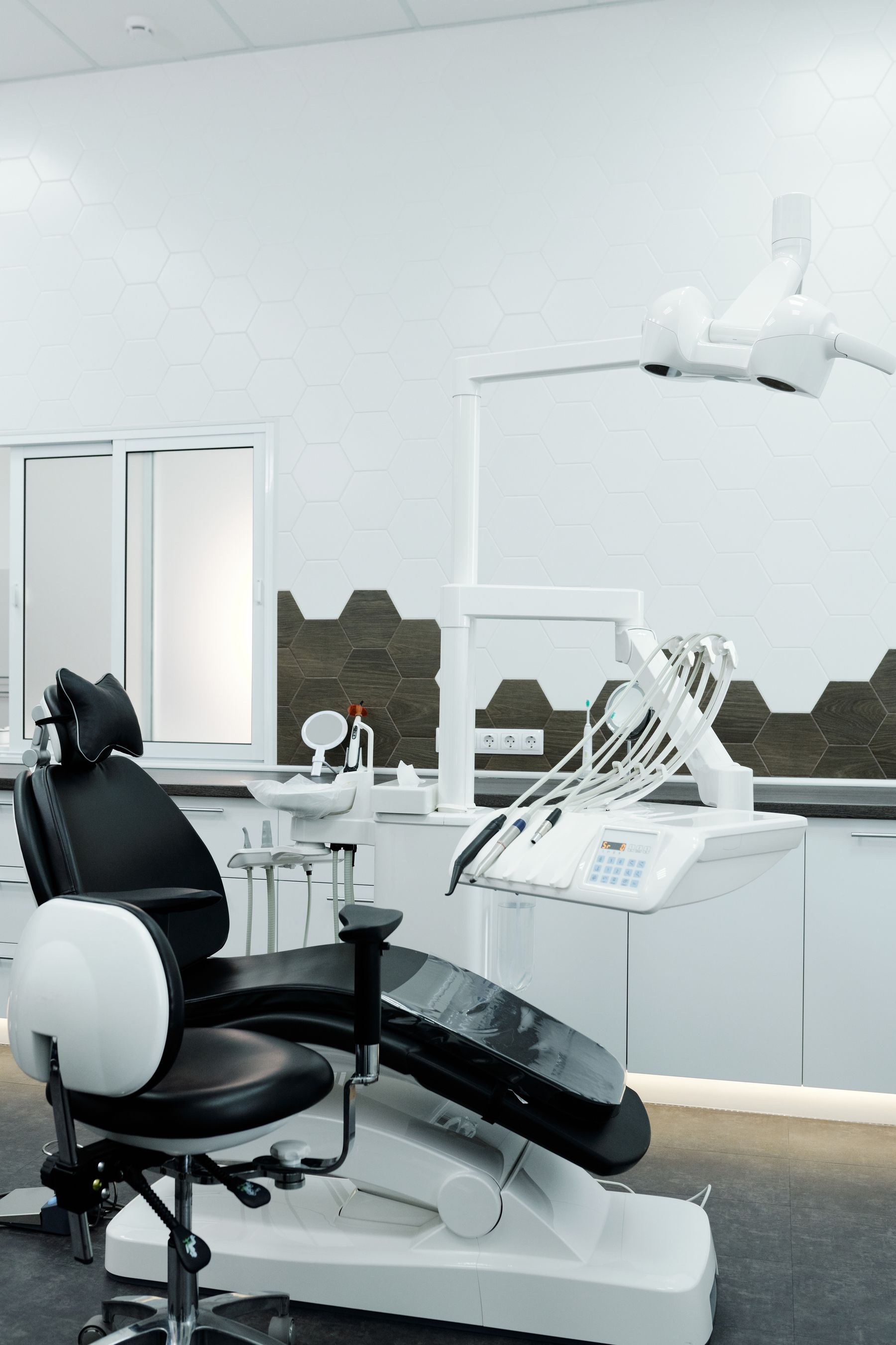 A bright dental clinic room with a treatment chair and equipment