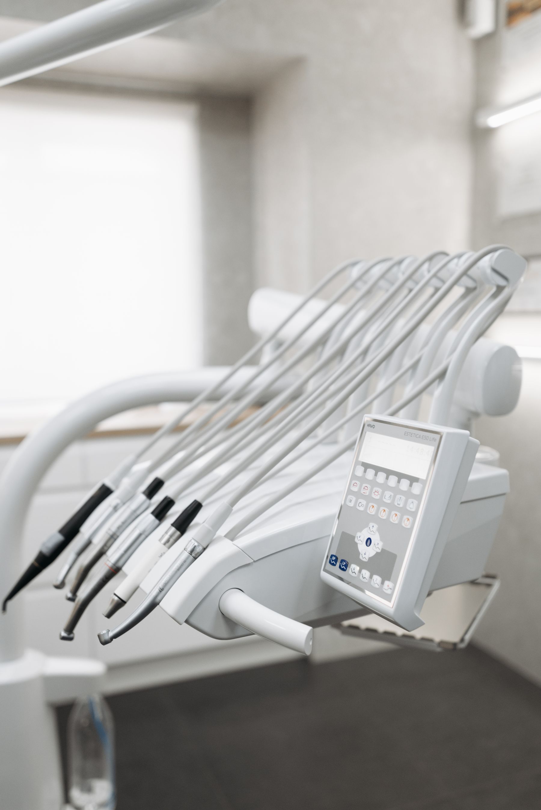 The handpiece console of a dental unit with drills and a syringe on their holders